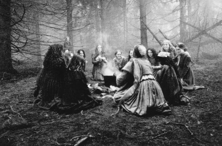 Un grupo de mujeres se reúne alrededor de una hoguera en medio del bosque.